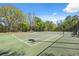 Community tennis court enclosed by fencing with court-side benches and surrounding trees at 15413 Azra Dr, Odessa, FL 33556