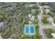 An aerial view showing tennis courts, basketball courts, pool, and tree-lined street at 18244 Autumn Lake Boulevard, Hudson, FL 34667