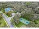 Aerial view of community courts, showing the tennis and basketball courts surrounded by verdant trees at 18244 Autumn Lake Boulevard, Hudson, FL 34667