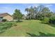 Sprawling backyard features lush lawn, mature trees, and a glimpse of the screened-in pool area at 18242 Autumn Lake Boulevard, Hudson, FL 34667