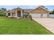 Charming single-story home with a two-car garage, blue door, and lush landscaping at 18244 Autumn Lake Boulevard, Hudson, FL 34667