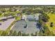 Overhead view of tennis courts and parking area within a community, set against a backdrop of mature trees at 18520 Hidden Pines Way, Hudson, FL 34667