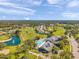 Aerial shot of a community with a pool, golf course, and surrounding lush green landscape under a bright sky at 18520 Hidden Pines Way, Hudson, FL 34667