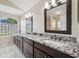 A double vanity bathroom with dark wood cabinets, granite counters, and a glass block window bringing in natural light at 18520 Hidden Pines Way, Hudson, FL 34667
