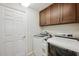 A well-organized laundry room featuring modern washer, dryer, and wooden upper cabinets at 18520 Hidden Pines Way, Hudson, FL 34667