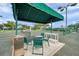 Covered seating area beside the tennis court with furniture, a clock, and visible surroundings at 18520 Hidden Pines Way, Hudson, FL 34667
