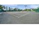 Well-maintained tennis court with lighting, green fencing, and a covered seating area, ideal for friendly matches at 18520 Hidden Pines Way, Hudson, FL 34667