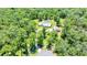 Aerial view of a large property with a house, detached garage, and screened pool surrounded by tall trees at 21000 Exeter Ct, Brooksville, FL 34601