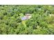 Aerial view of a large property with house, detached garage and screened pool among tall trees at 21000 Exeter Ct, Brooksville, FL 34601