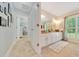 Bright bathroom featuring a double vanity with gold hardware and a view to the backyard at 21000 Exeter Ct, Brooksville, FL 34601