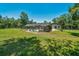 View of a screened pool, house and fenced-in yard surrounded by large trees on a sunny day at 21000 Exeter Ct, Brooksville, FL 34601