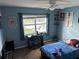 Well-lit bedroom with a desk, fan, window, and blue walls at 2158 Clayton Ave, Spring Hill, FL 34609
