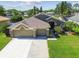 Aerial view of a home with a well-manicured lawn and a three-car garage in a sunny neighborhood at 22431 Willow Lakes Dr, Lutz, FL 33549