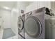 Modern laundry room with gray washer and dryer, cabinets, and white tile floors at 22431 Willow Lakes Dr, Lutz, FL 33549