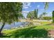 Scenic view of a serene pond surrounded by lush greenery and a white fence on a sunny day at 22431 Willow Lakes Dr, Lutz, FL 33549