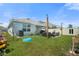 Landscaped backyard with a patio shaded by a sunshade, modern seating, and well-maintained lawn at 33592 Barberry Leaf Way, Wesley Chapel, FL 33543