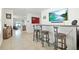 Stylish bar area with three stools, a mounted TV, and views into the adjacent rooms at 33592 Barberry Leaf Way, Wesley Chapel, FL 33543
