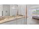 Bathroom featuring dual sinks, a large mirror, and access to the bedroom at 33592 Barberry Leaf Way, Wesley Chapel, FL 33543
