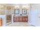 A bathroom featuring double sinks, a tile shower, decorative mirrors, and neutral colored tile flooring at 3546 Flamingo Blvd, Hernando Beach, FL 34607
