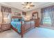 A bedroom with a decorative wooden bed frame, windows with curtains, ceiling fan, and carpet flooring at 3546 Flamingo Blvd, Hernando Beach, FL 34607