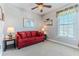 Cozy living room featuring a comfortable red sofa, ceiling fan, and a bright window with natural light at 3546 Flamingo Blvd, Hernando Beach, FL 34607