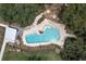 Aerial view of community pool with surrounding deck, lounge chairs, and lush greenery at 3767 Dragonfly Trl, Odessa, FL 33556