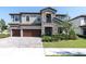 Two-story home featuring a three car garage, stone facade, and covered entry at 3767 Dragonfly Trl, Odessa, FL 33556