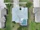 An aerial view of a private backyard featuring a screened-in pool and patio area, surrounded by lush landscaping at 4048 St Ives Blvd, Spring Hill, FL 34609