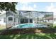 A clear in-ground pool and spa are enclosed by a screen, with an open-plan house visible through the sliding door at 4048 St Ives Blvd, Spring Hill, FL 34609