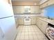Bright kitchen features white cabinets, white appliances, tile backsplash and tile flooring at 4823 Ebbtide Ln # 105, Port Richey, FL 34668