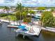 Waterfront home with private dock featuring boat lift, patio with lounge seating, and tropical landscaping at 4917 Marlin Dr, New Port Richey, FL 34652