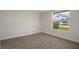 Well-lit bedroom with a large window offering a pleasant outdoor view of landscaping and clear skies at 4937 Dory Dr, New Port Richey, FL 34652
