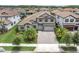 Aerial view of a two-story home with a tile roof, a three-car garage, and a beautifully landscaped yard at 5001 Night Star Trl, Odessa, FL 33556