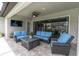Covered outdoor patio boasts comfortable seating area, ceiling fan and mounted television at 5001 Night Star Trl, Odessa, FL 33556