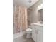 Bathroom with a bathtub and shower, marble-top vanity and toilet with seashell patterned shower curtain at 5045 Pelican Dr, New Port Richey, FL 34652