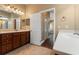 Bright bathroom featuring double sinks, tile flooring, wood cabinetry, and a doorway leading to the hallway at 5487 Valley View Dr, Brooksville, FL 34601