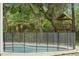 Pool with protective safety fence overlooks mature trees and backyard playhouse at 5487 Valley View Dr, Brooksville, FL 34601