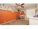 Charming bedroom with dinosaur-themed decor, complete with custom orange paint and ceiling fan at 6309 Covewood Dr, Spring Hill, FL 34609