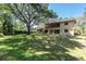 A sprawling backyard showcases a two-story home with a balcony, enhanced by lush greenery and mature trees at 6454 Summerfield Loop, Trinity, FL 34655
