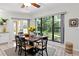 Bright dining area featuring a wooden table, modern chairs, a large window with a backyard view, and ample natural light at 6454 Summerfield Loop, Trinity, FL 34655