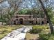 Stunning home with a stone entryway and arched windows along a drive surrounded by mature trees at 6454 Summerfield Loop, Trinity, FL 34655