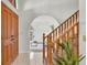 Inviting foyer showcases tile flooring, staircase with wooden railing, and an arched doorway to the living room at 6454 Summerfield Loop, Trinity, FL 34655