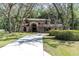 Beautiful two-story home boasts a long driveway, arched entryway, mature trees, and well-manicured lawn at 6454 Summerfield Loop, Trinity, FL 34655