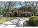 Lovely two-story home featuring a long driveway, arched entryway, mature trees, and lush landscaping at 6454 Summerfield Loop, Trinity, FL 34655