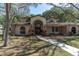 Charming two-story home featuring a long walkway, arched entryway, mature trees, and well-maintained landscaping at 6454 Summerfield Loop, Trinity, FL 34655