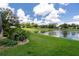 Backyard overlooking a lake with lush lawn and manicured landscaping at 7175 Bottle Brush Dr, Spring Hill, FL 34606