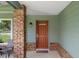 Charming front porch with a red entry door and brick accents at 7175 Bottle Brush Dr, Spring Hill, FL 34606