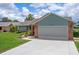 View of the two-car garage with brick supports and well maintained landscaping at 7175 Bottle Brush Dr, Spring Hill, FL 34606