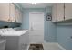 Well-lit laundry room with overhead cabinets and a washer and dryer at 7175 Bottle Brush Dr, Spring Hill, FL 34606