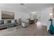 Bright living room featuring wood-look floors and a view of the screened pool and patio through large windows at 7175 Bottle Brush Dr, Spring Hill, FL 34606